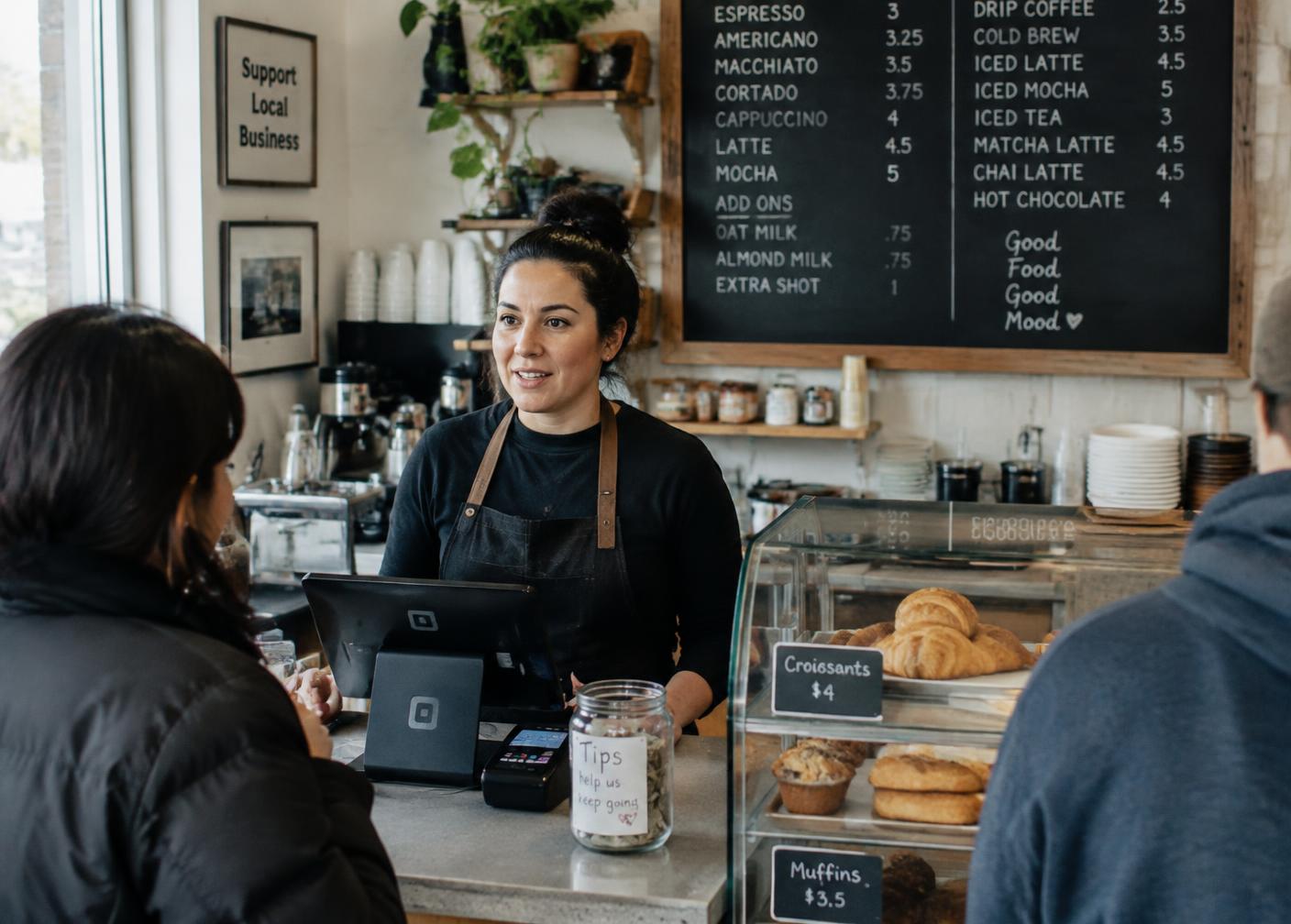 Small business owner serving a customer at a neighborhood cafe counter